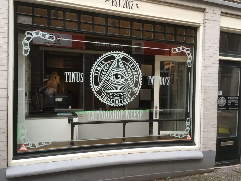 Etalage van Tinus Tattoos aan de Slijkstraat in Weesp met het oog-logo